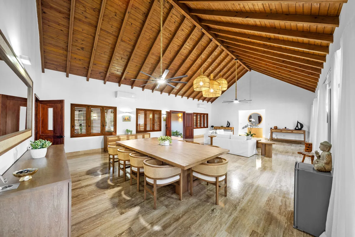 Open great room with timber ceiling, dining table and adjoining living area