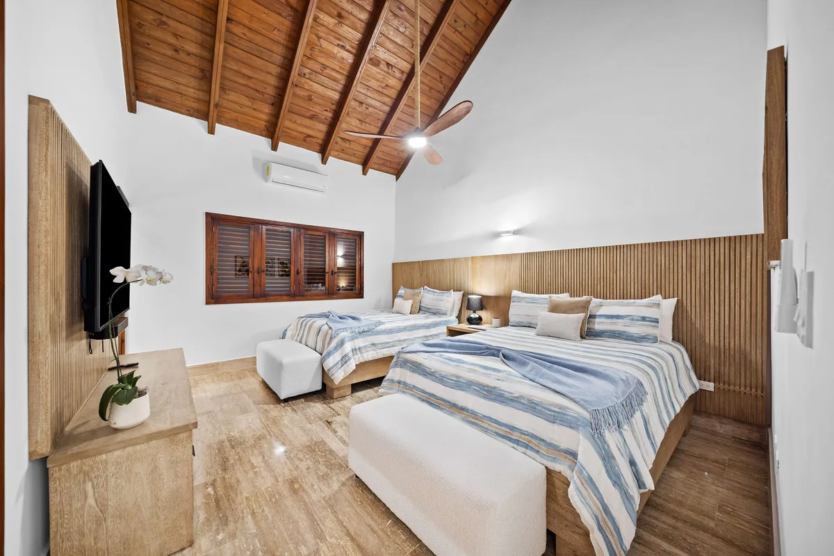 Guest bedroom with two queen beds, wood accents and vaulted ceiling