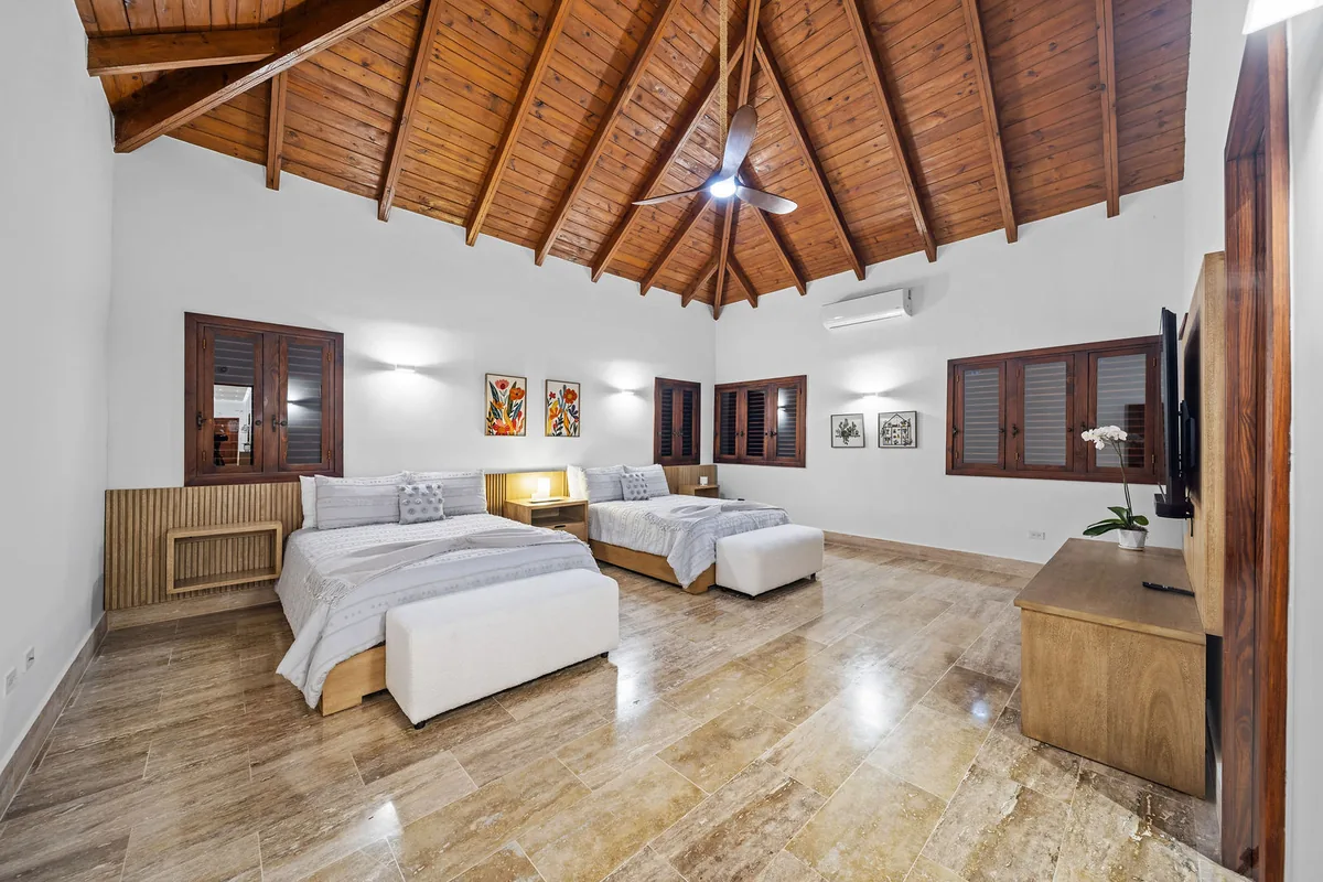 Spacious guest bedroom with two queen beds and timber ceiling