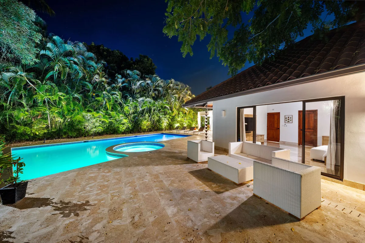 Illuminated pool and guest pavilion surrounded by palms