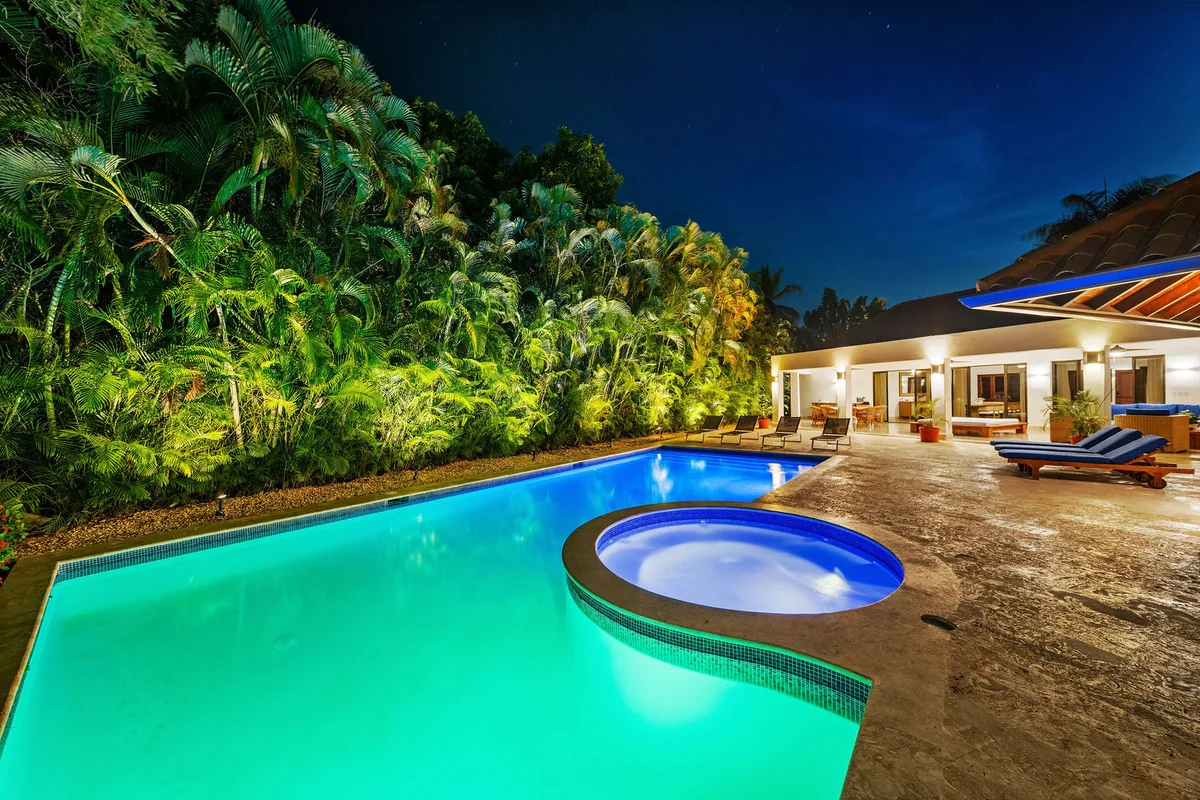 Wide evening view across the pool and integrated jacuzzi toward the covered terrace