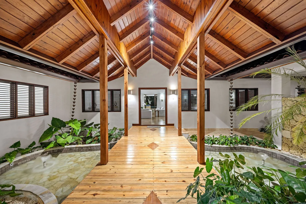 Timber-roofed entrance bridge over a planted interior garden