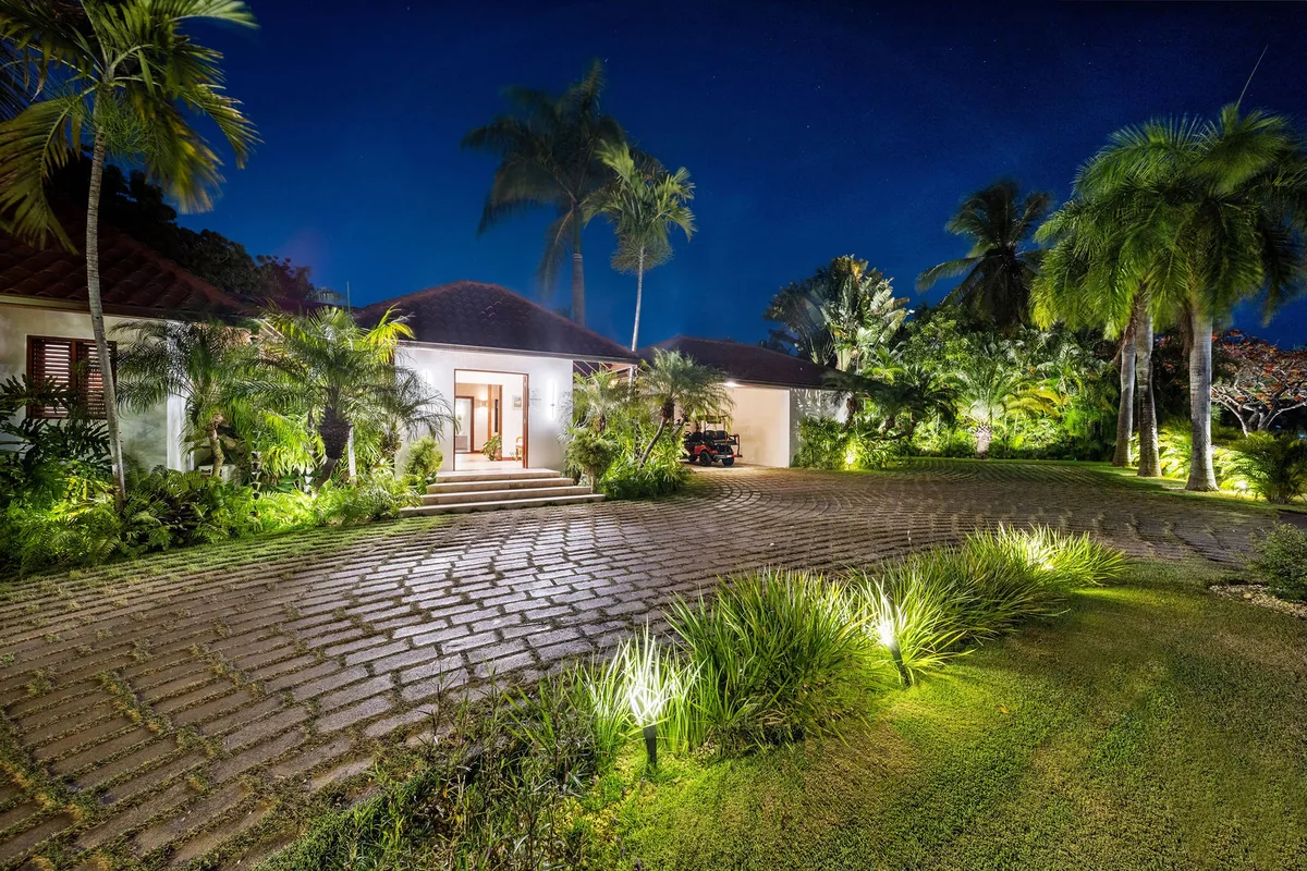 Palm-lined arrival courtyard and illuminated villa entrance