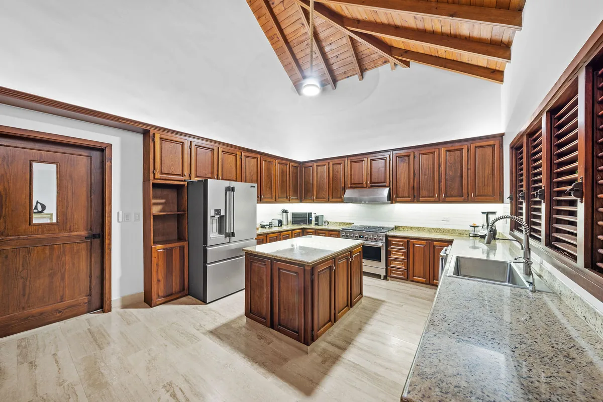 Full kitchen with wood cabinetry, island, range and dual sinks