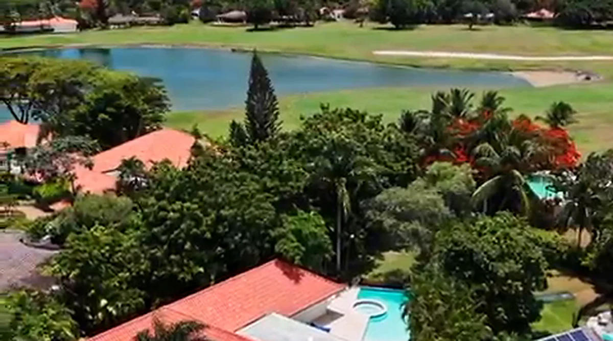 Elevated view from Los Lagos 17 across the tropical canopy toward the lake and golf course